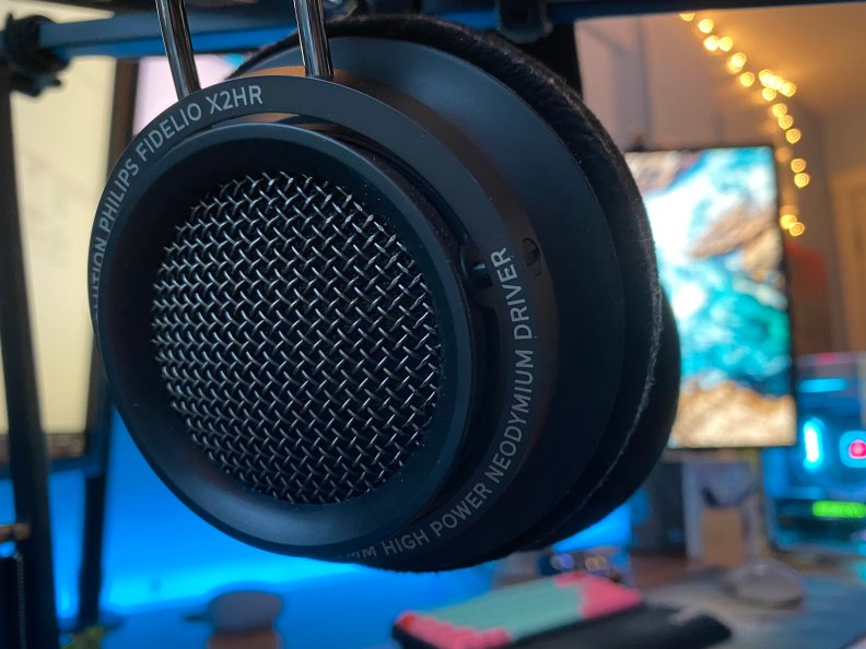 Open back headphones with a PC setup in the background.